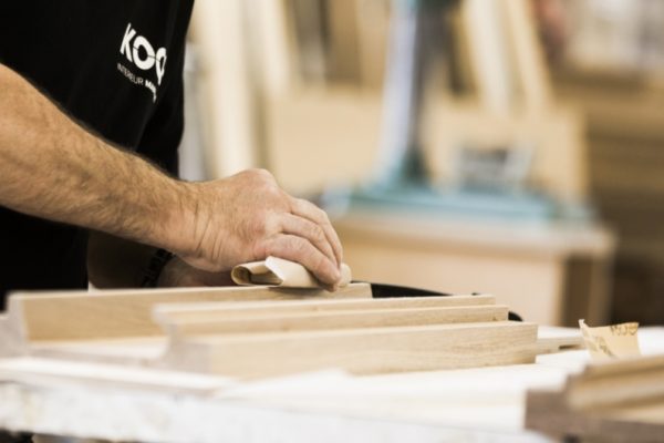 Koch Mitarbeiter glättet Holz